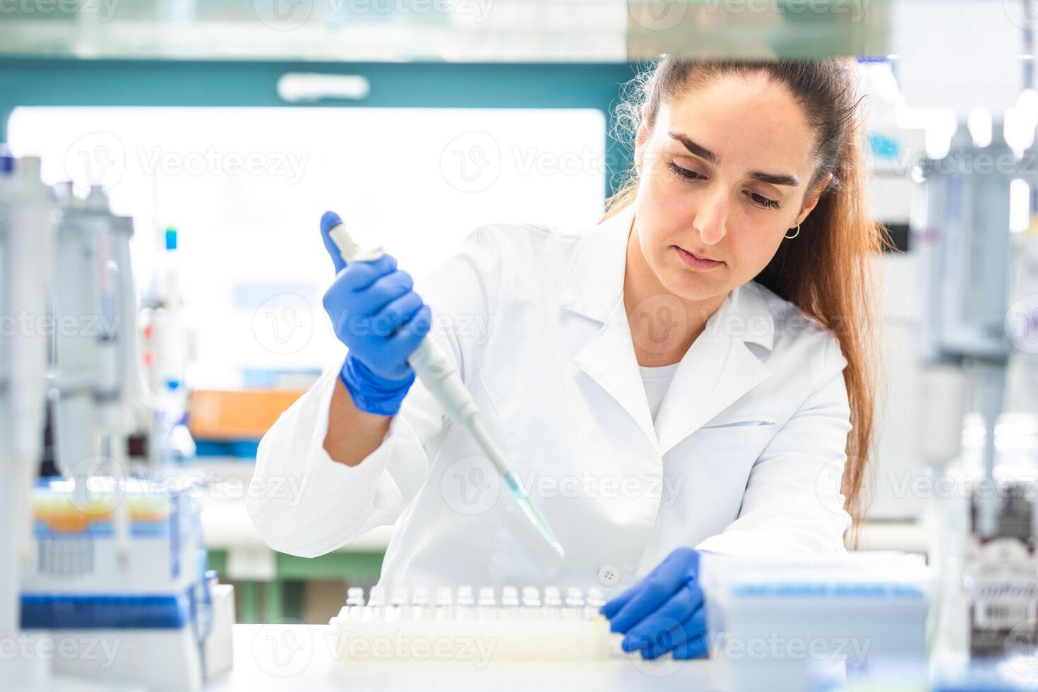 Scientist with dropper dripping liquid into a test tube in scientific laboratory, concept of pharmaceutical environment photo