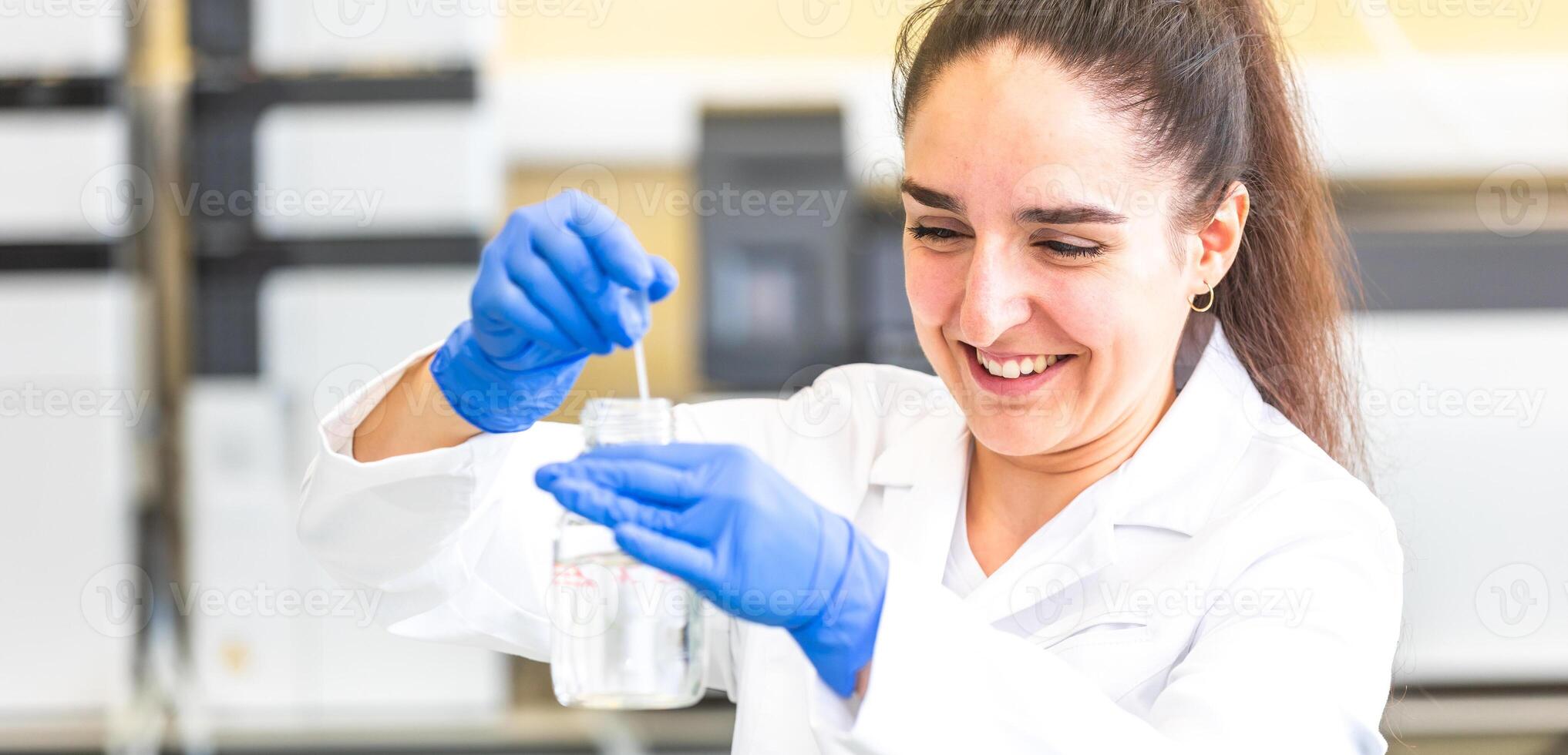 Scientist with dropper dripping liquid into a test tube in scientific laboratory, concept of pharmaceutical environment photo