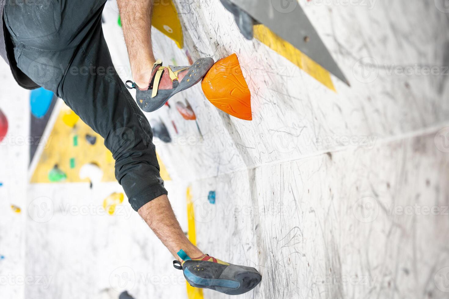 Young climber climbing on the boulder wall indoor, rear view, concept of extreme sports and bouldering photo
