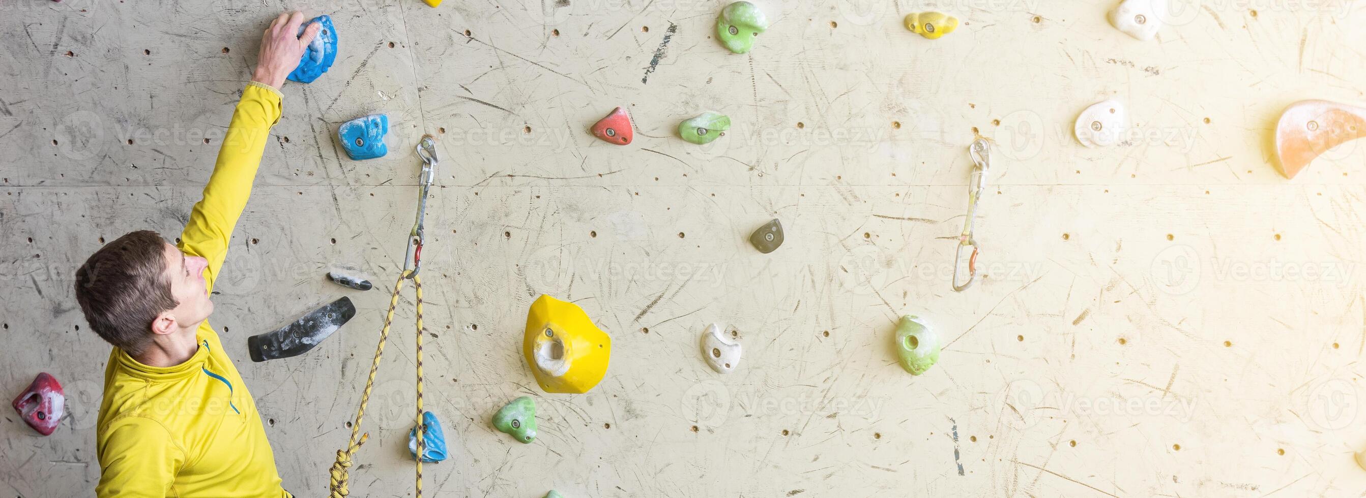 Young climber climbing on a boulder wall indoor, rear view, concept of extreme sports and bouldering photo