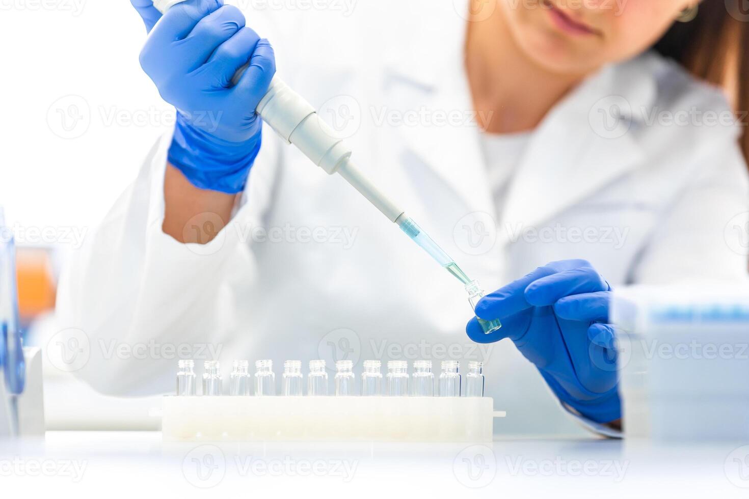 Scientist with dropper dripping liquid into a test tube in scientific laboratory, concept of pharmaceutical environment photo