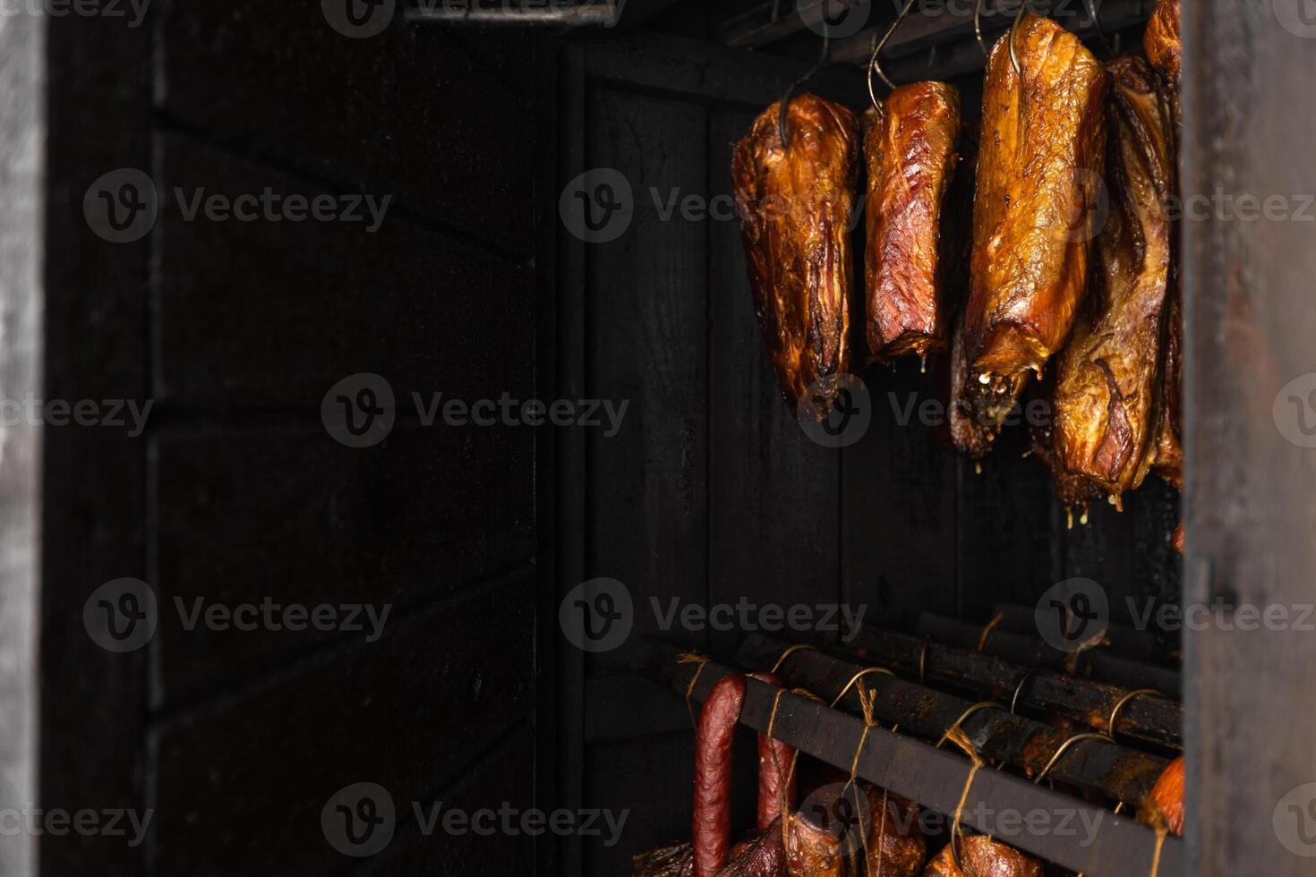 Close up of smoked meat and belly or beech meat with dark crust in the smokehouse or smoker, food concept photo