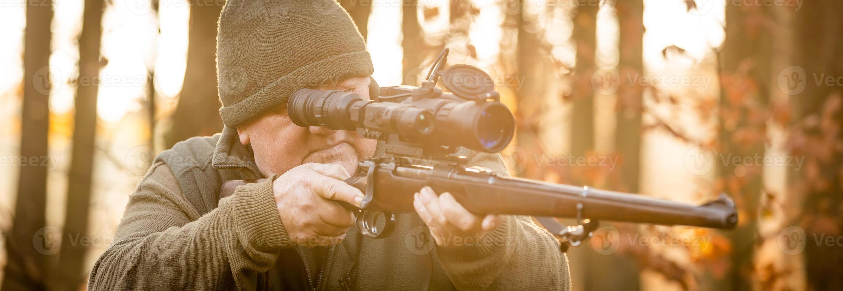 Hunter or ranger with professional, nightvision hunting gun aiming wild animal and hunting form to hunt in an autumn forest, hunting concept photo
