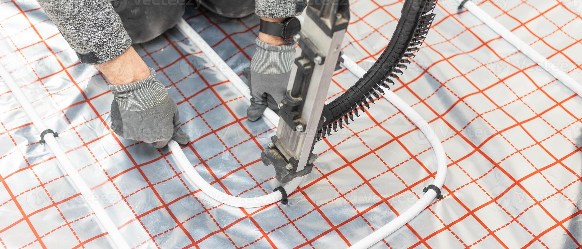 Worker installing underfloor heating system, water heating on the new residential house, concept of heated floor photo