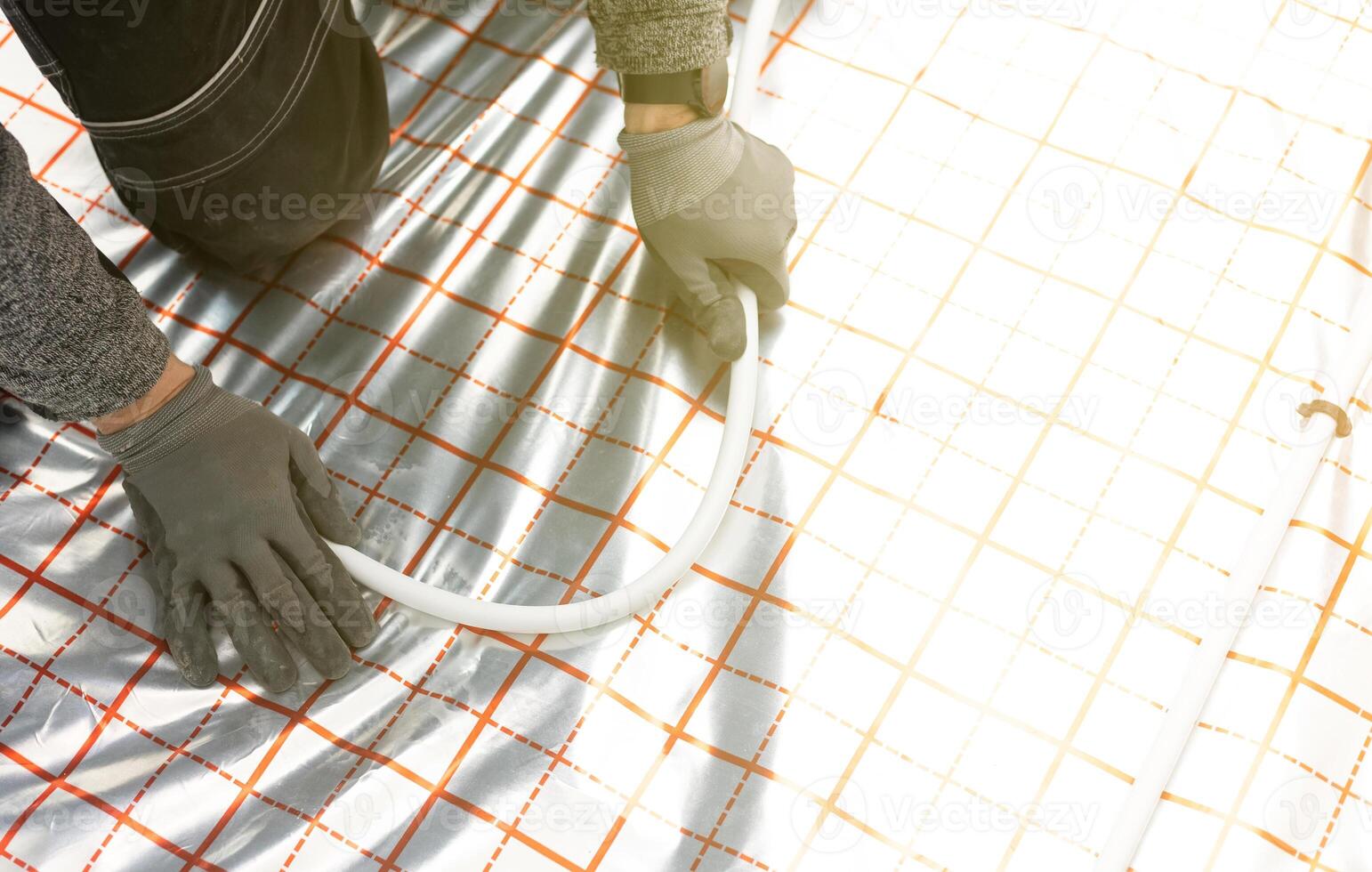 Worker installing underfloor heating system, water heating on the new residential house, concept of heated floor photo