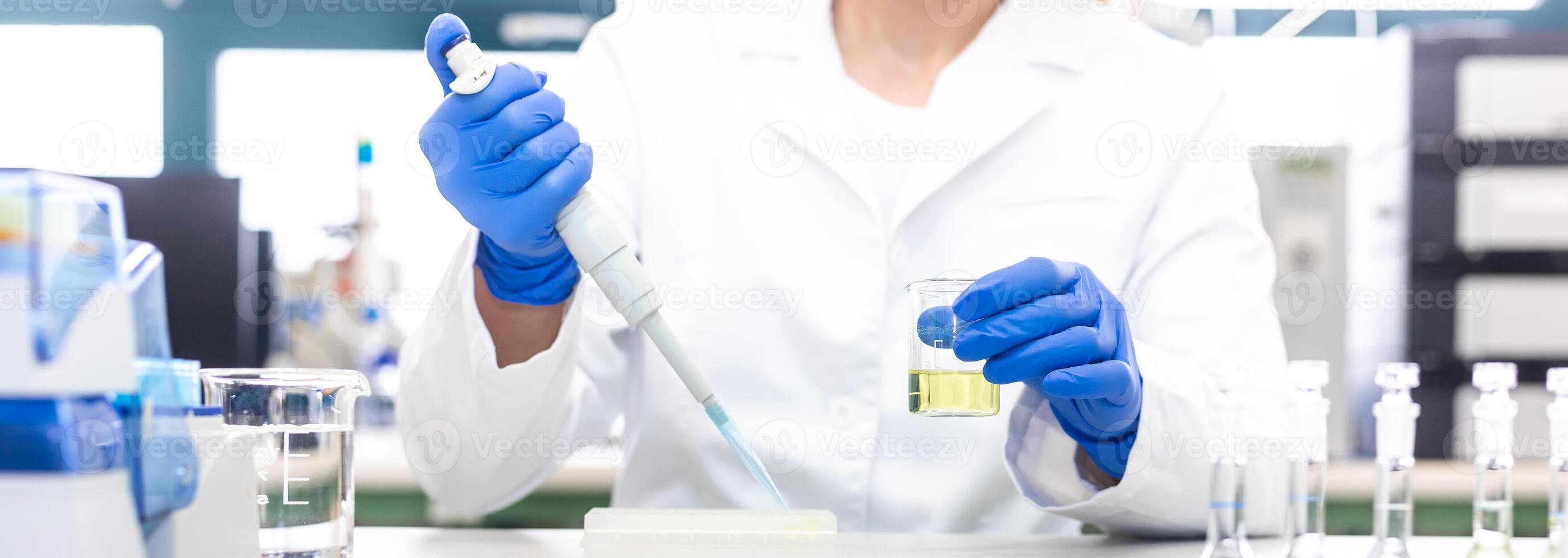 Scientist with dropper dripping liquid into a test tube in scientific laboratory photo