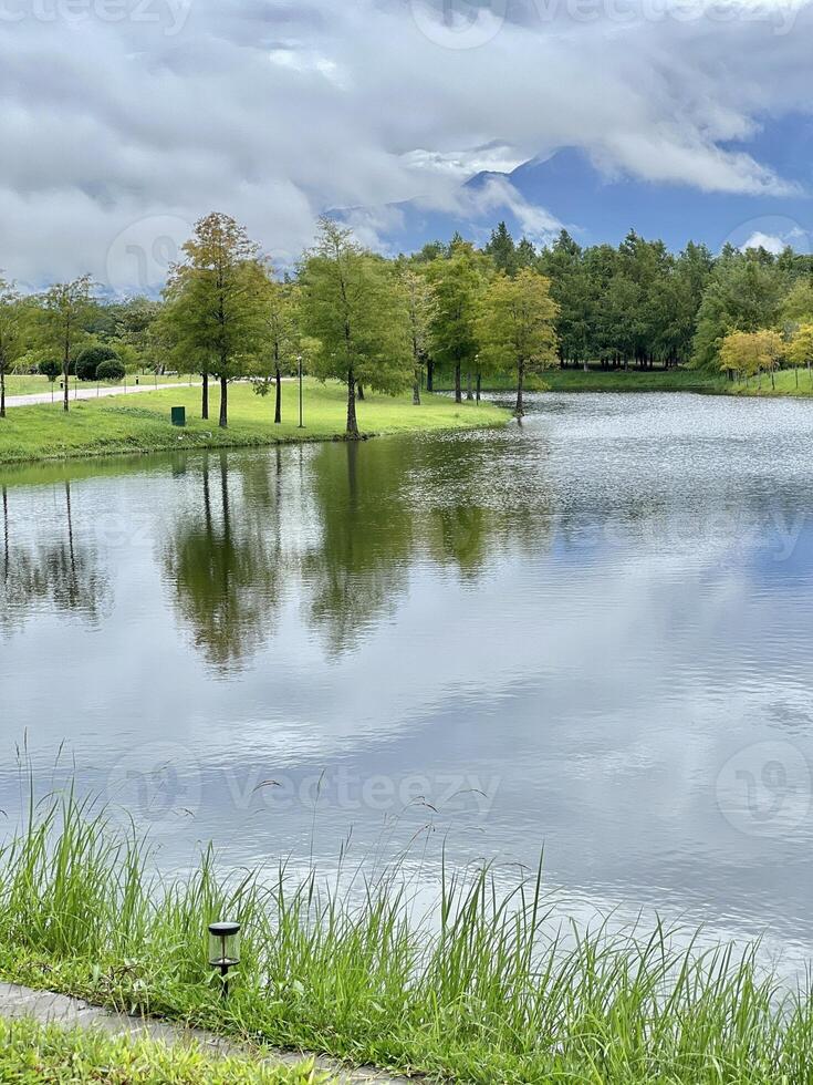 Scenic View of a Serene Lake with Lush Forest and Mist-Shrouded Mountains photo