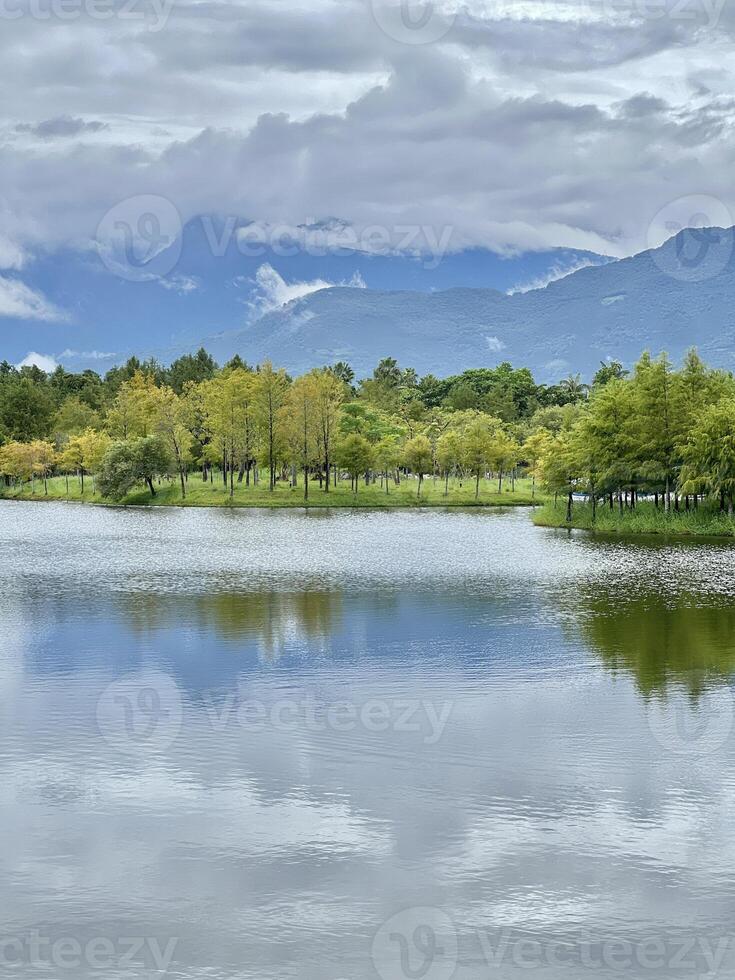 Scenic View of a Serene Lake with Lush Forest and Mist-Shrouded Mountains photo