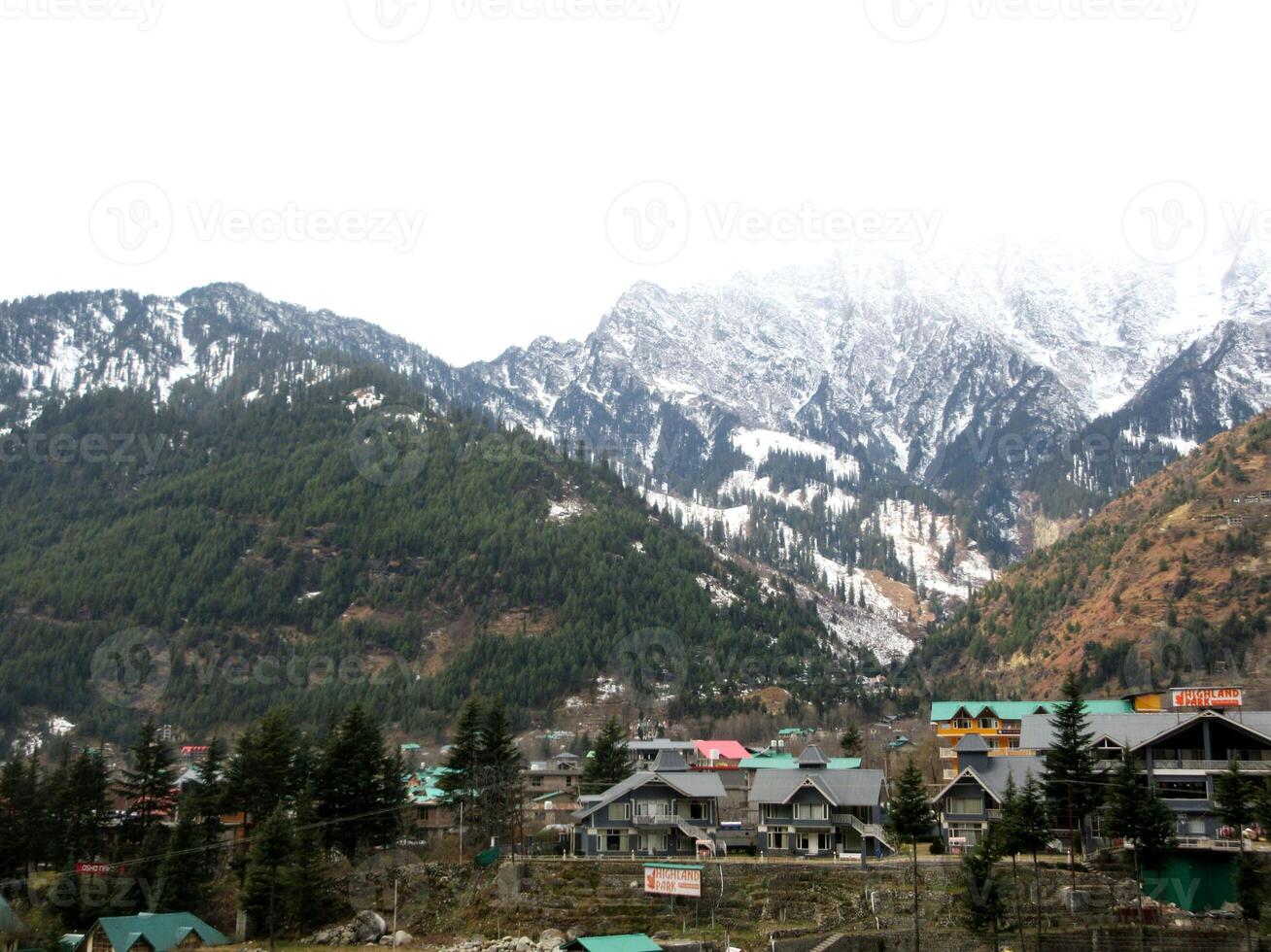 Dark cloudy Sky with snow-covered mountains and tall trees in Himachal Pradesh India photo