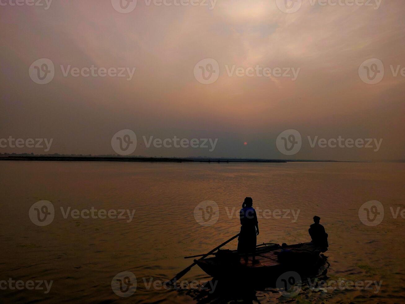 People fishing on a boat during dawn time in Ganga river photo