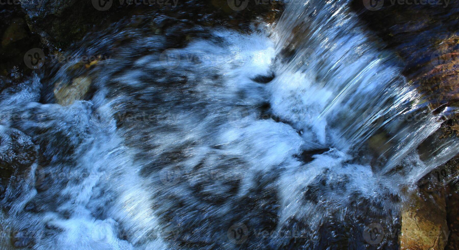 The flow of water in a small waterfall in mountain creek top view photo