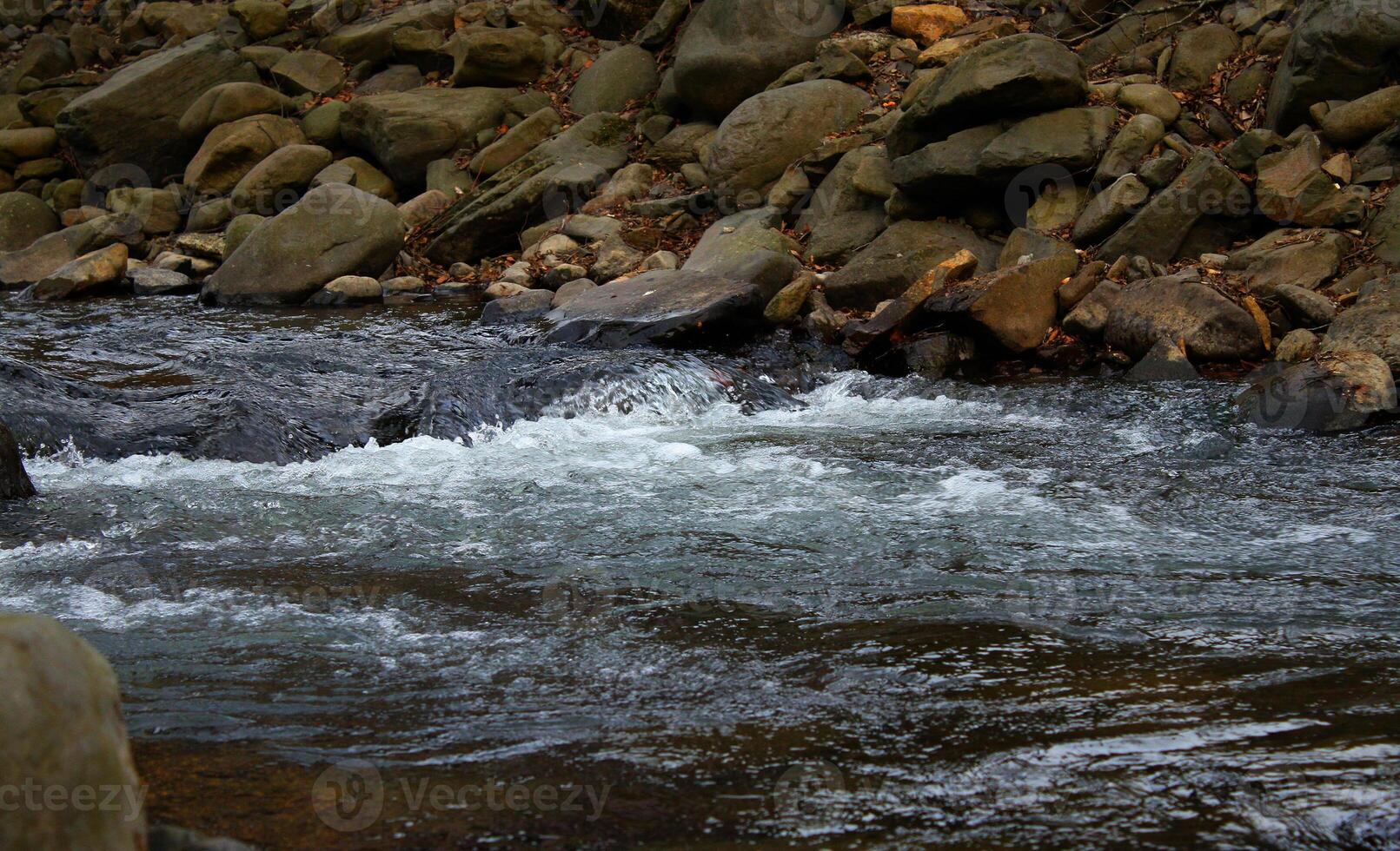 Rivulet on a small mountain river running between rocky shores photo