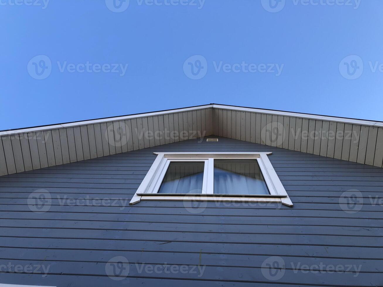 window on the gable of a country house, blue sky, low angle view photo