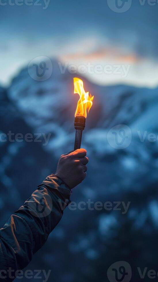 Hand holding torch illuminates mountain landscape at dusk. Symbolizing hope, resilience, and adventure themes. photo