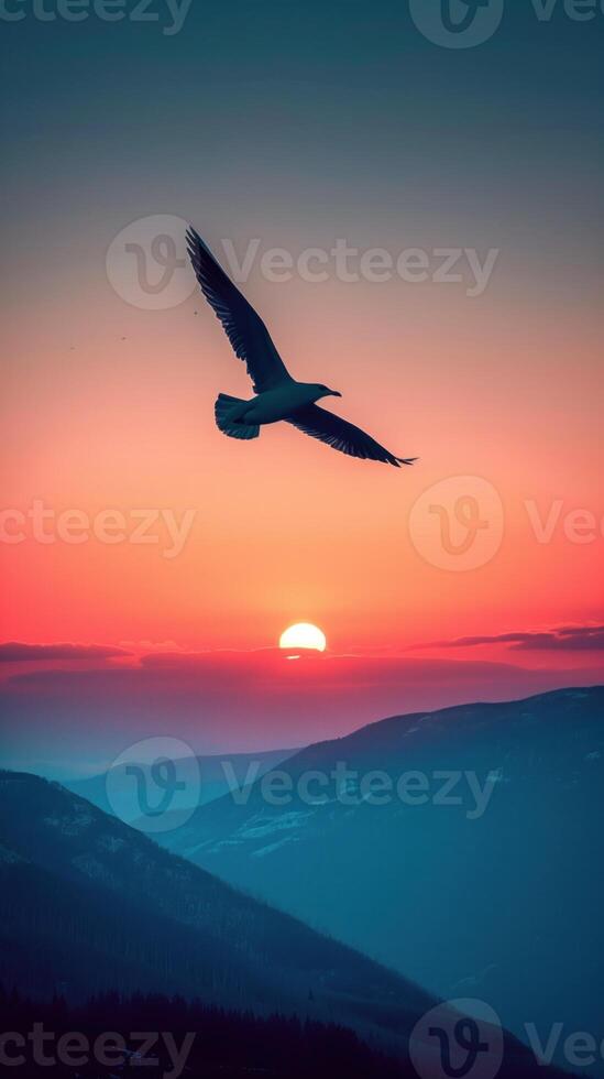 Silhouette of bird against a mountain sunset horizon. photo