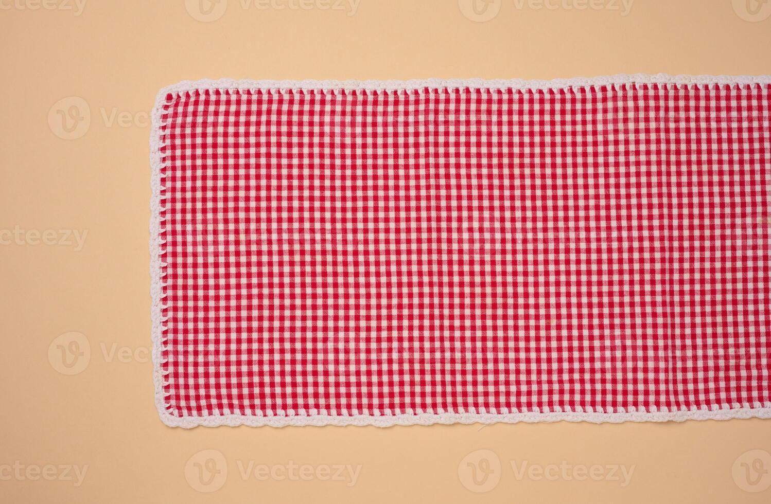 Folded red kitchen towel on a brown background, top view photo