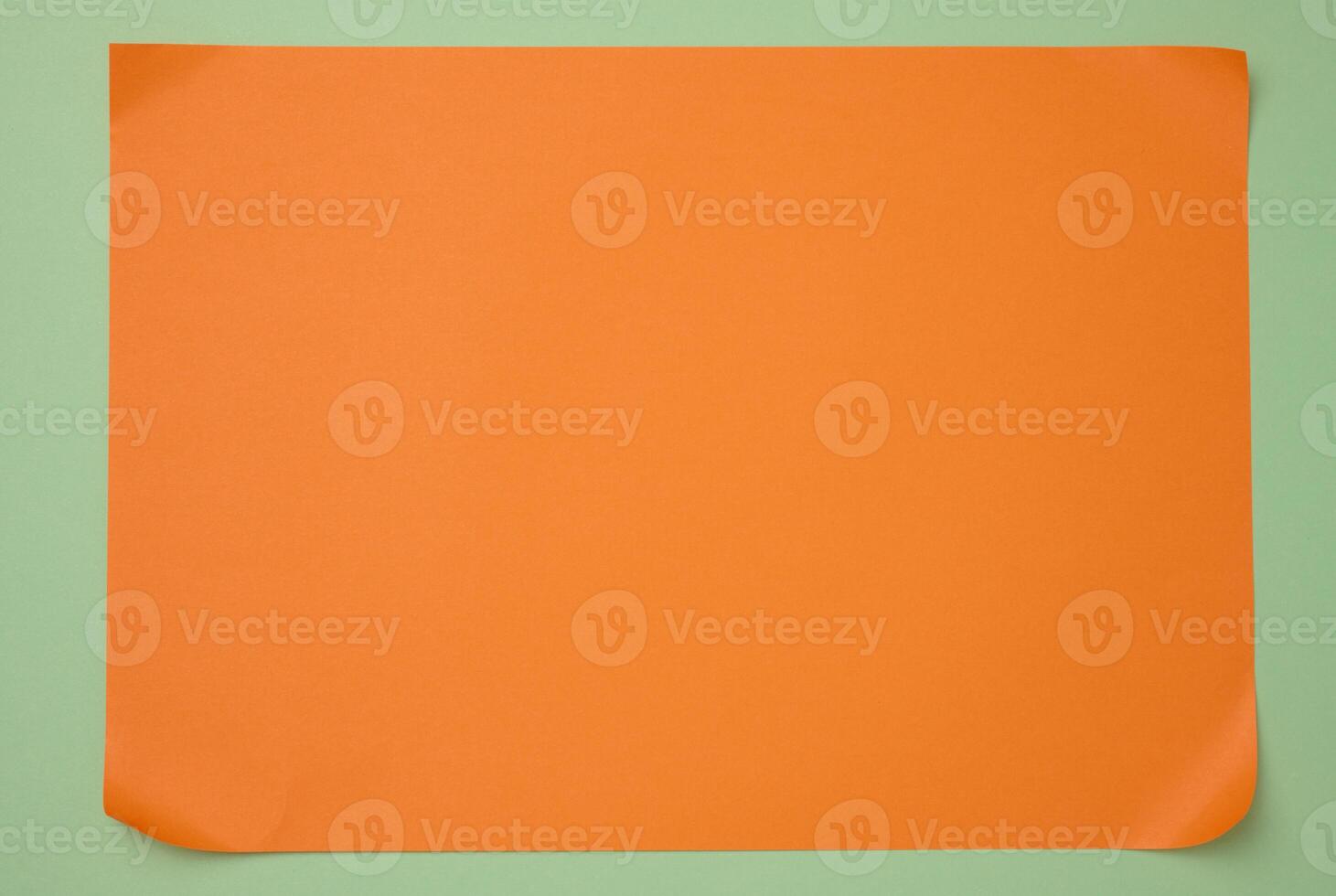 Blank orange sheet of paper on green background, abstract backdrop for inscription, copy space photo