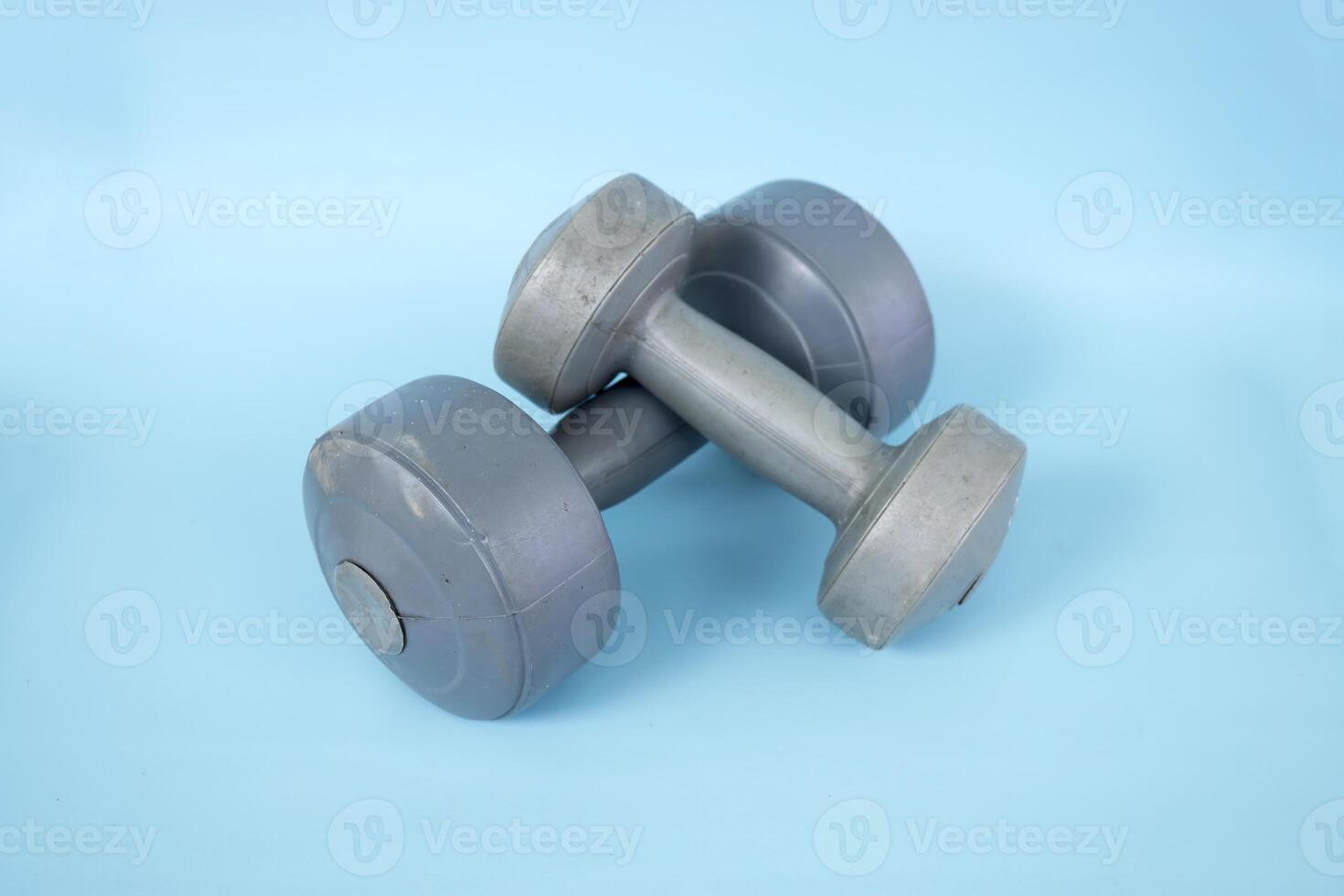 Two silver plastic dumbbells isolated on a blue background photo