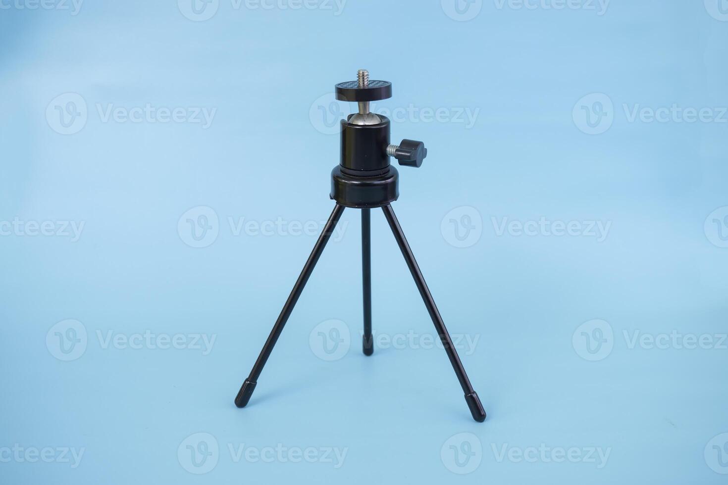 Black mini tripod with steel case and ballhead isolated on blue background photo