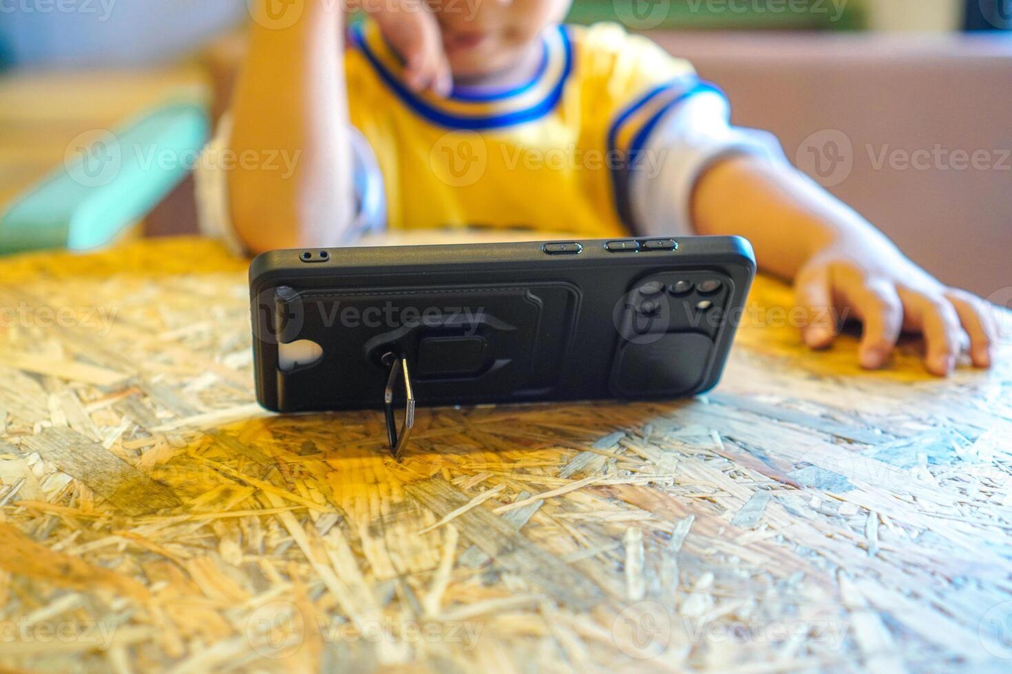 toddler watching cartoons on smartphone with stand phone case photo