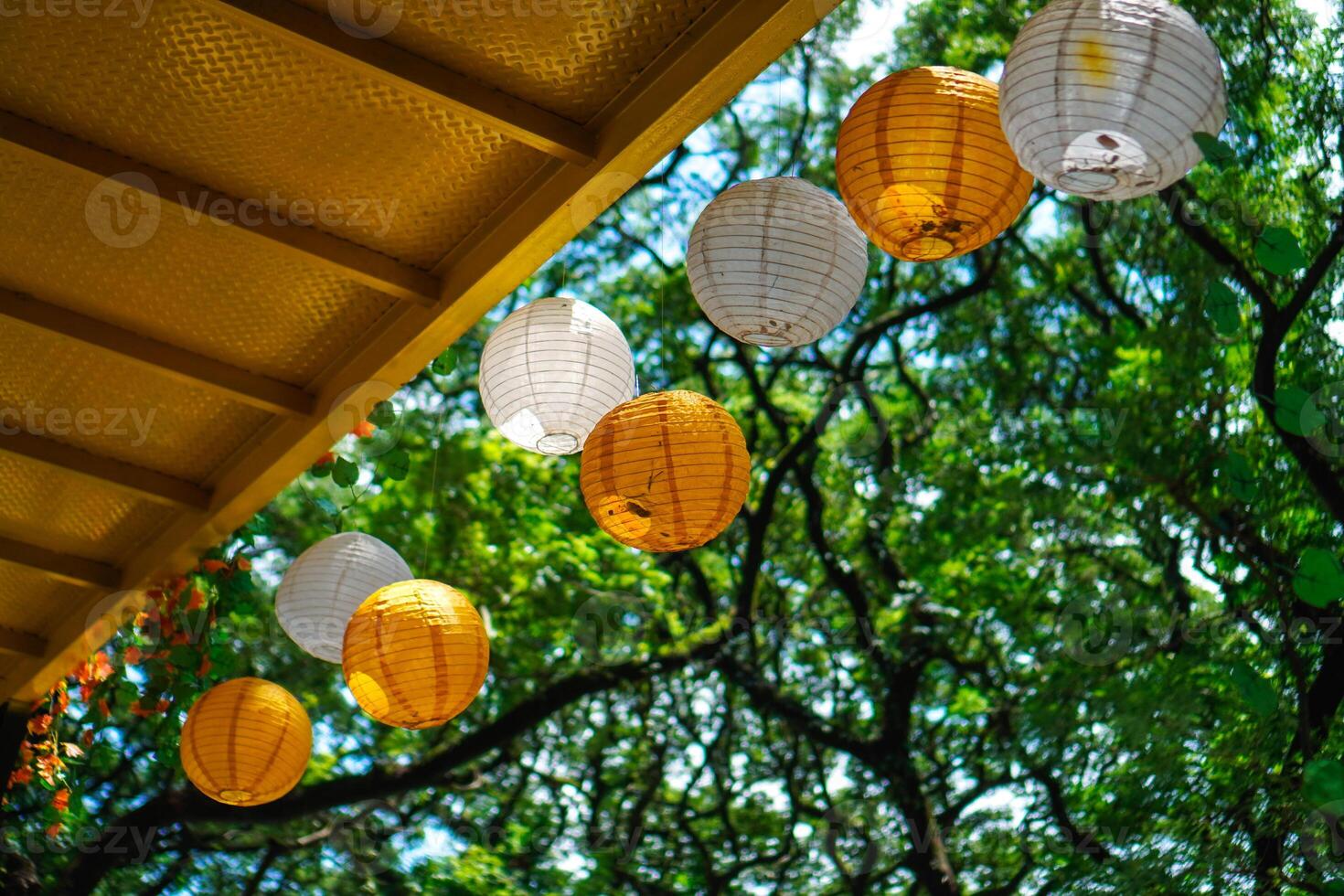 Lanterns are hung under the bridge with a background of sky and green trees photo
