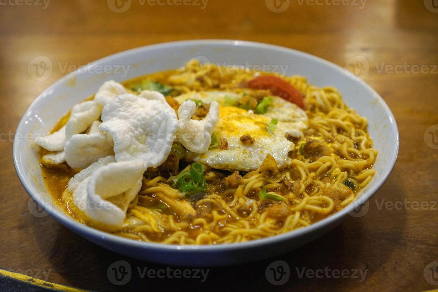 Javanese godok noodles topped with egg, shredded chicken, crackers photo