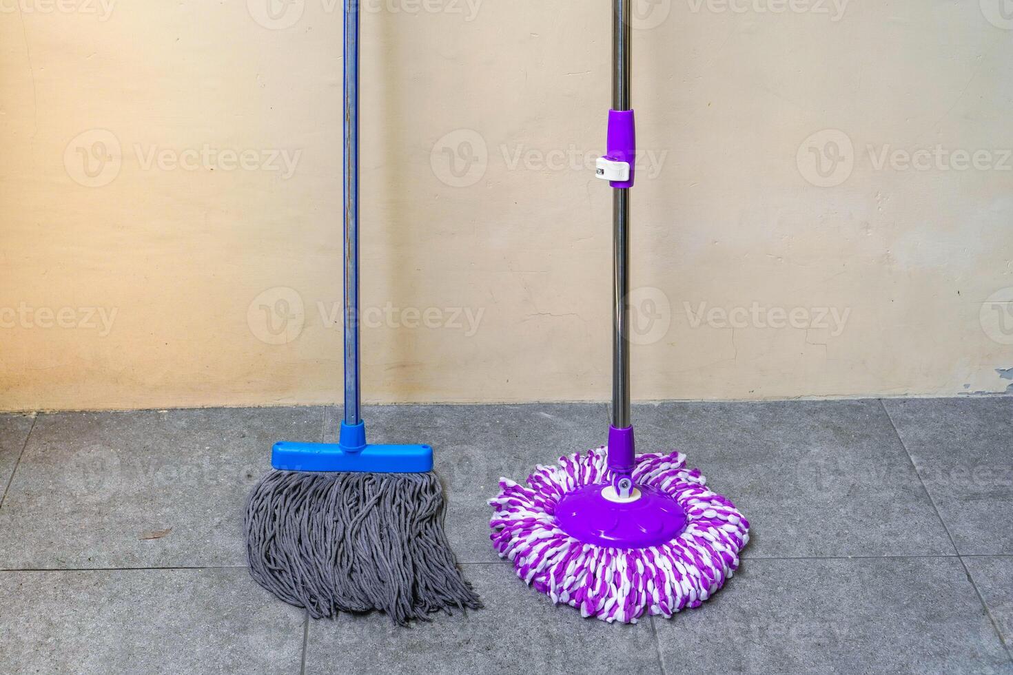 two simple, modern floor mops leaned against the wall photo