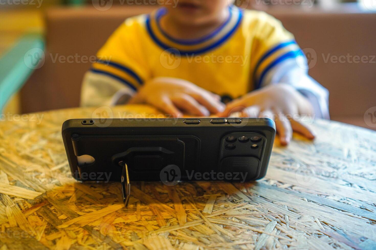 toddler watching cartoons on smartphone with stand phone case photo