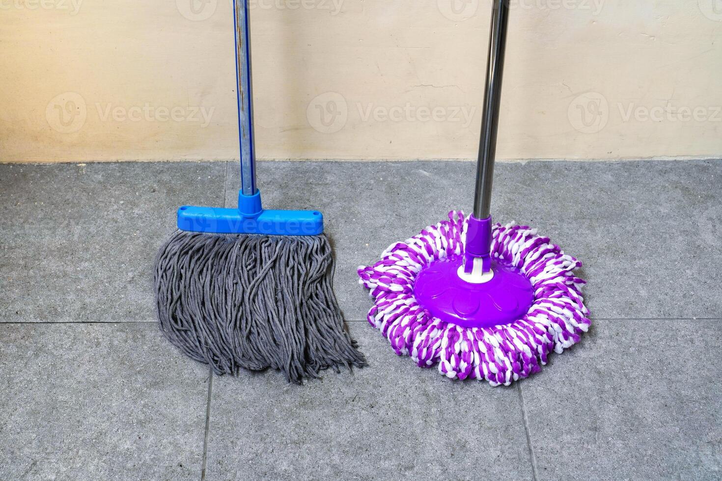 two simple, modern floor mops leaned against the wall photo