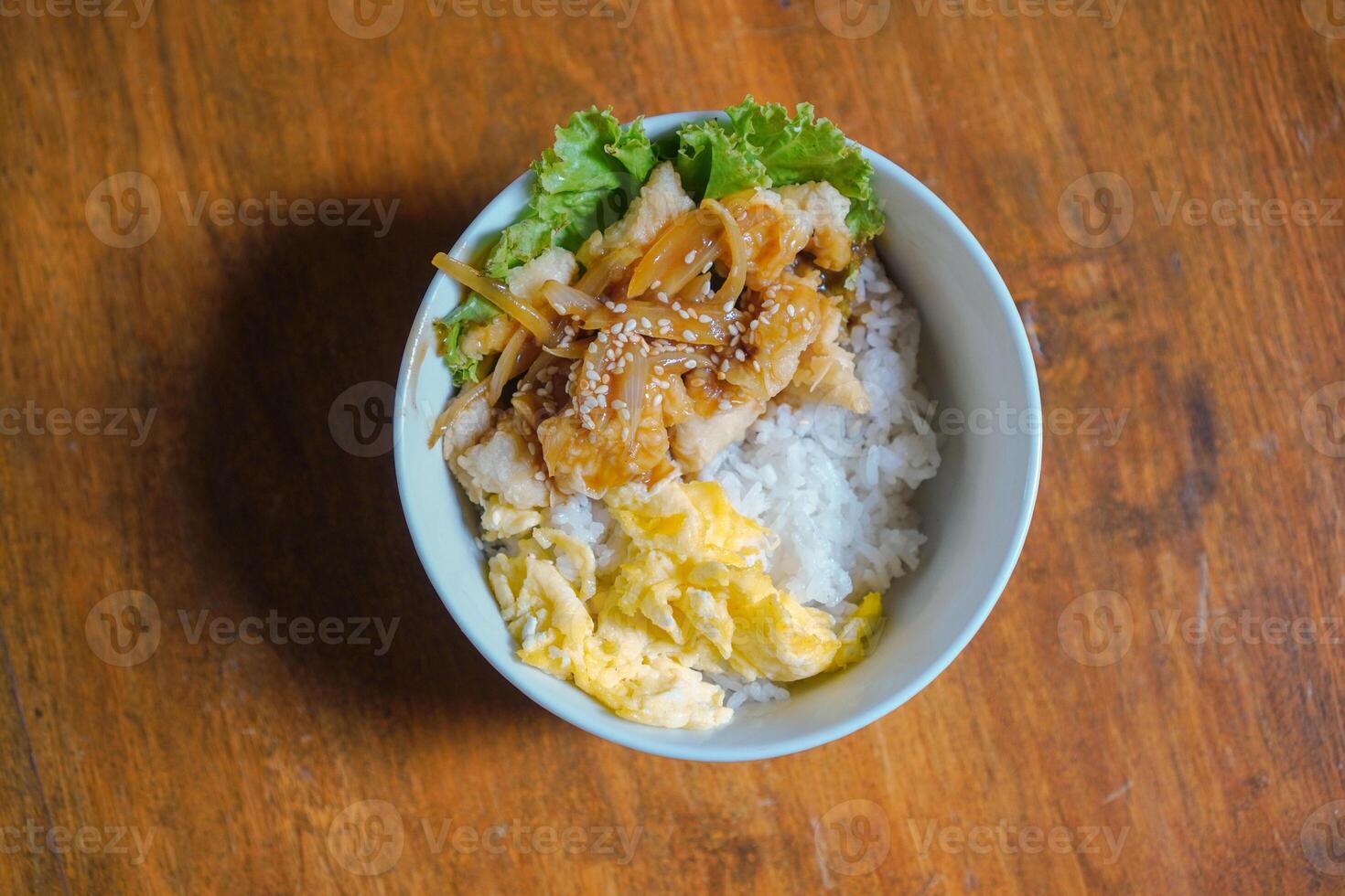 Chicken karage rice and teriyaki sauce sprinkled with sesame seeds on food packaging on a wooden table background photo