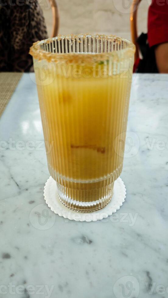 Refreshing Citrus Mocktail with Brown Sugar Rim on Marble Table with Lime Slice Topping photo