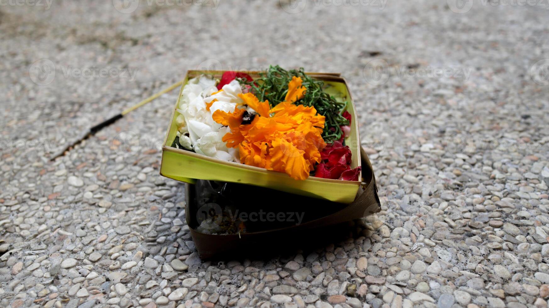 Beautifully Arranged Balinese Offering Basket with Colorful Flowers on Pebbled Ground for Traditional Hindu Rituals in Bali. photo