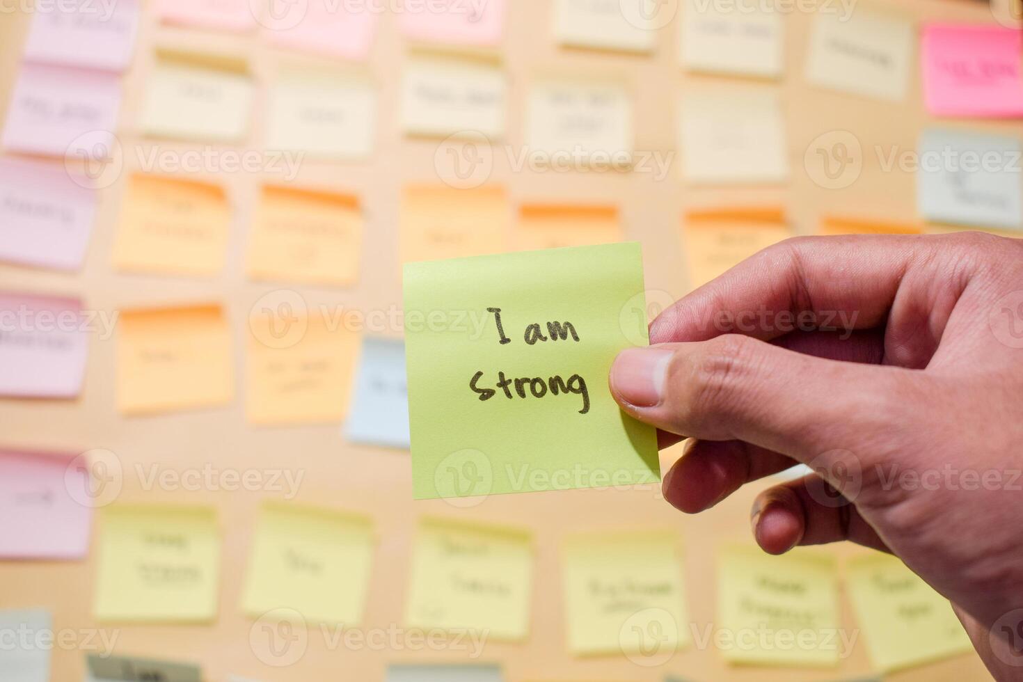 Hand hold sticky notes with words I am strong, Motivational for personal development, inspirational handwriting. Sticky notes background photo