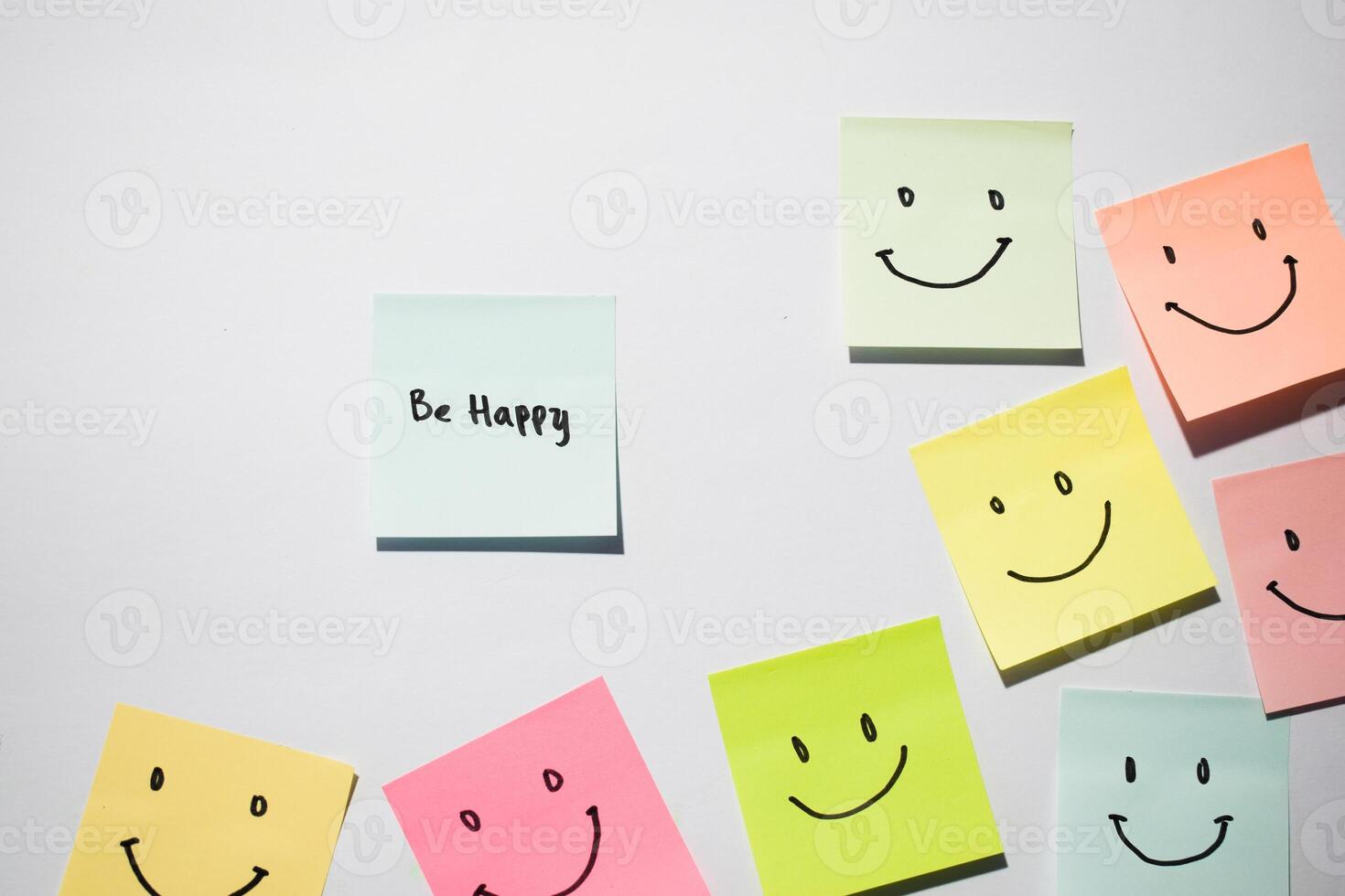 Be Happy and smile emoticon on sticky notes. Motivational words for personal development, inspirational handwriting. Isolated on background photo