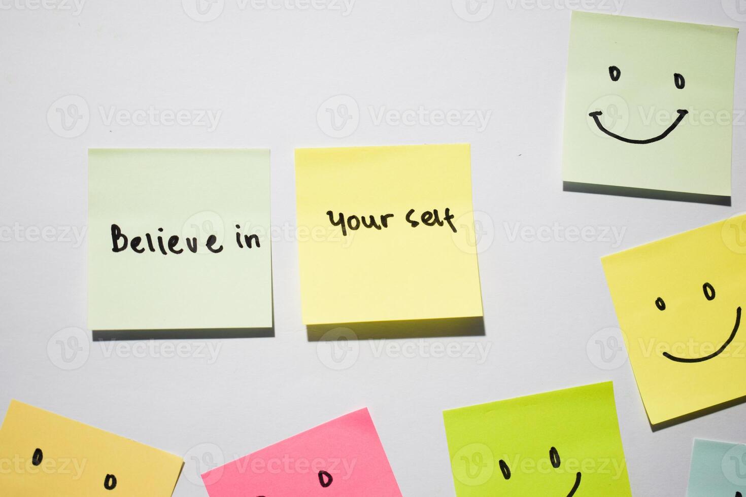 Believe in yourself and smile emoticon on sticky notes. Motivational words for personal development, inspirational handwriting. Isolated on background photo
