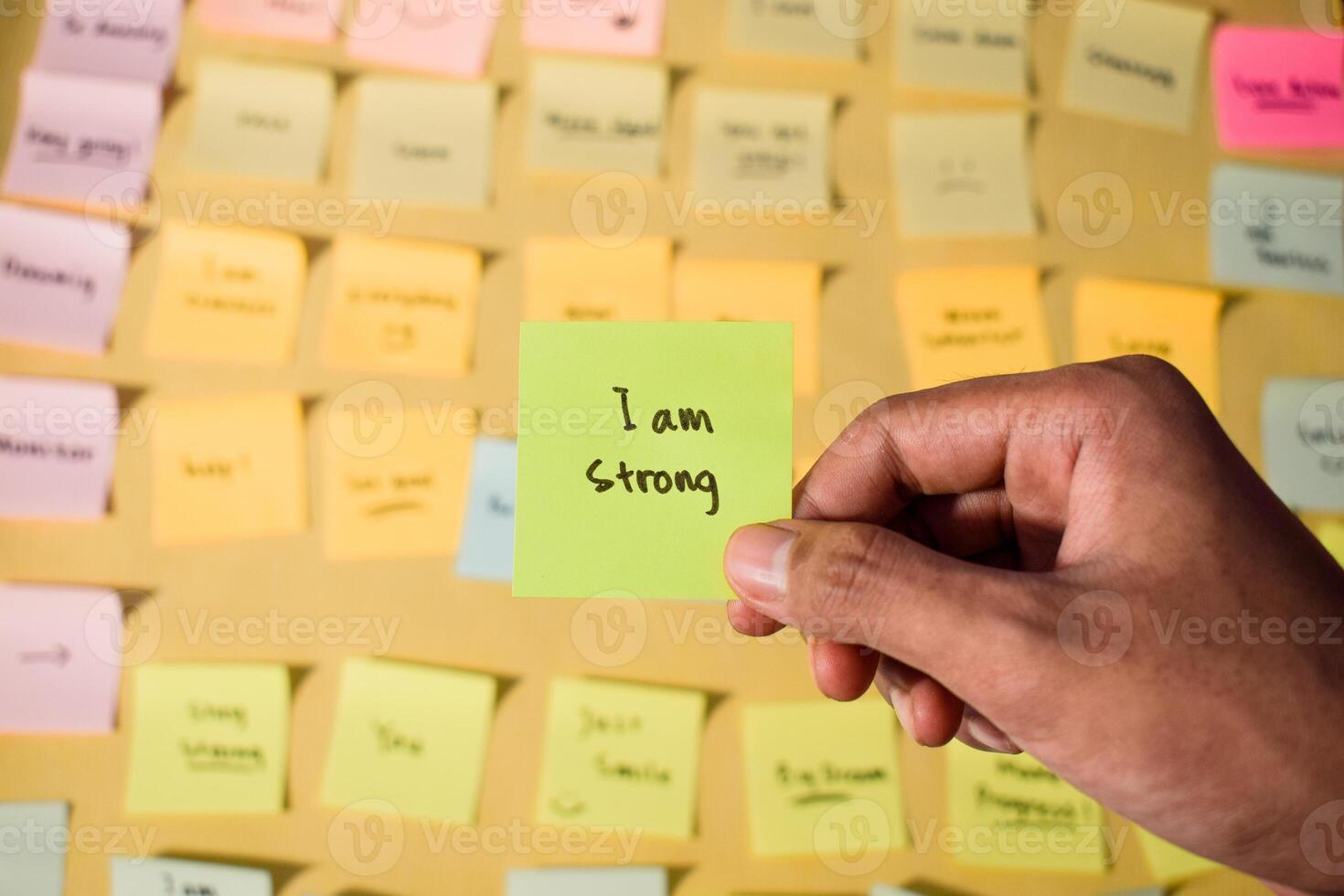 Hand hold sticky notes with words I am strong, Motivational personal development, inspirational handwriting. Sticky notes background photo