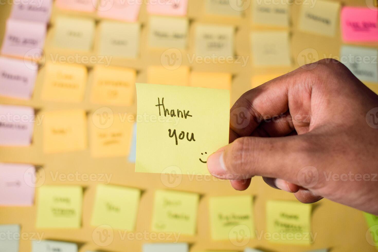 Hand hold sticky notes with words Thank you. Motivational words for personal development, inspirational handwriting. Sticky notes background photo