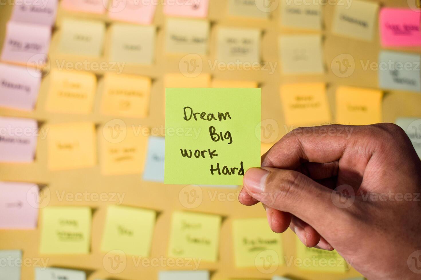 Hand hold sticky notes with words Dream Big, Work Hard. Motivational words for personal development, inspirational handwriting. Sticky notes background photo