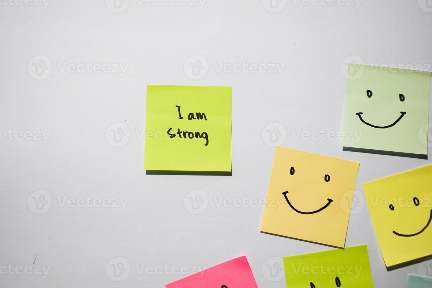I am strong and smile emoticon on sticky notes. Motivational words for personal development, inspirational handwriting. Isolated on background photo