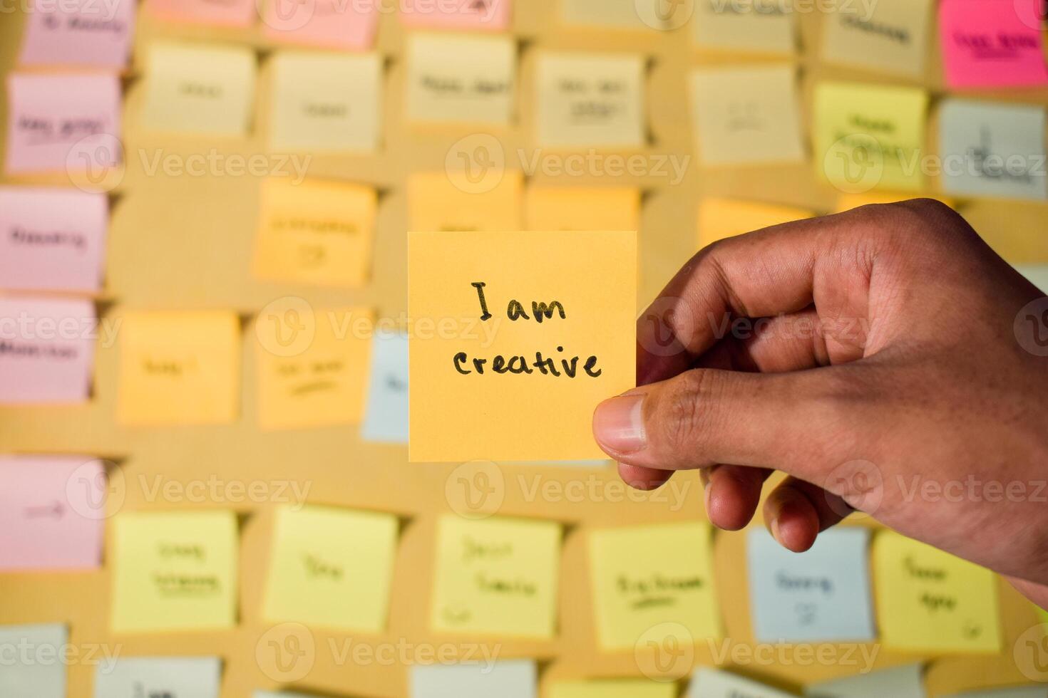 Hand hold sticky notes with words I am creative. Motivational words for personal development, inspirational handwriting. Sticky notes background photo