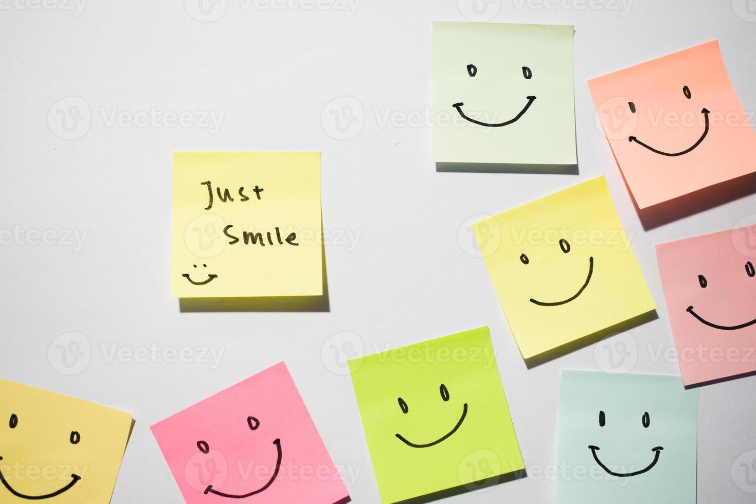 Just Smile and smile emoticon on sticky notes. Motivational words for personal development, inspirational handwriting. Isolated on background photo