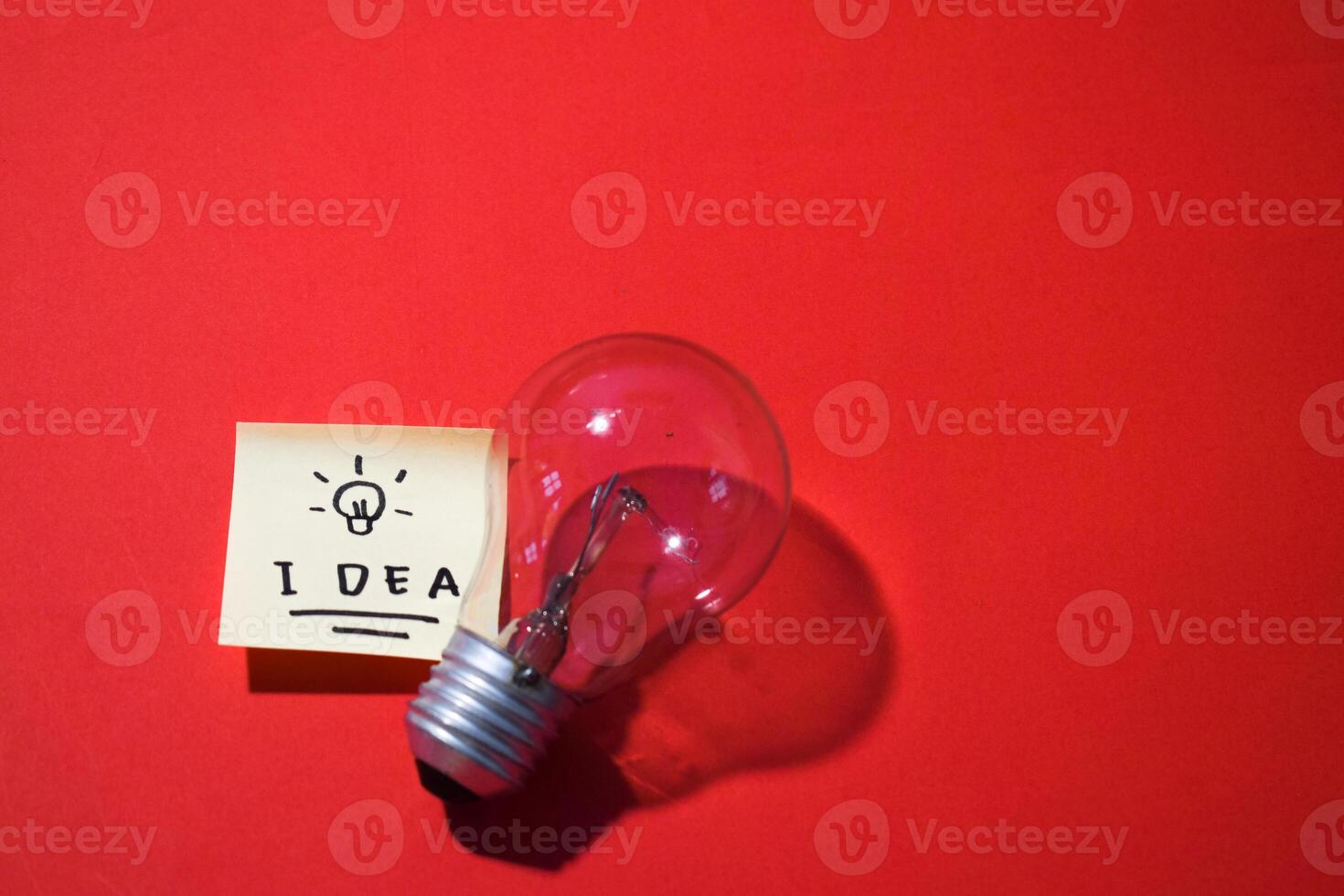 Idea on sticky notes and lightbulb. Isolated red background and copy space photo