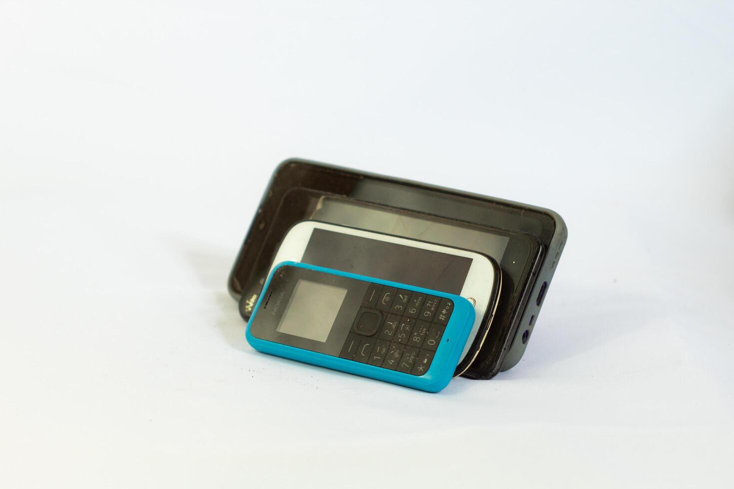 several phones tilted and photographed close up from a side angle with an isolated background photo
