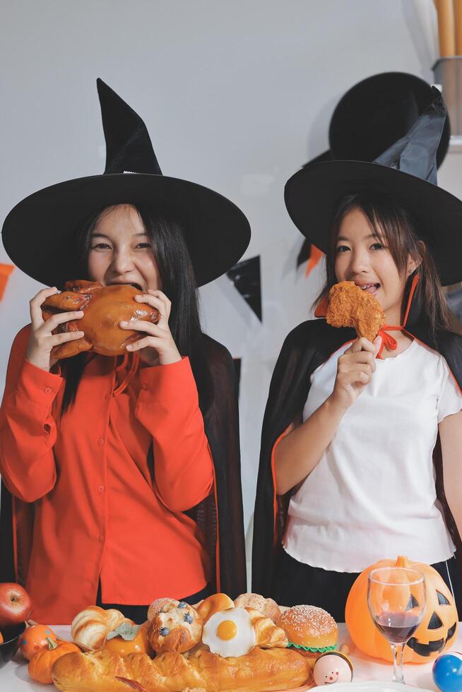 friendship, holiday and people concept - group of happy smiling friends in halloween costumes of vampire, devil, witch and cheetah at home party photo