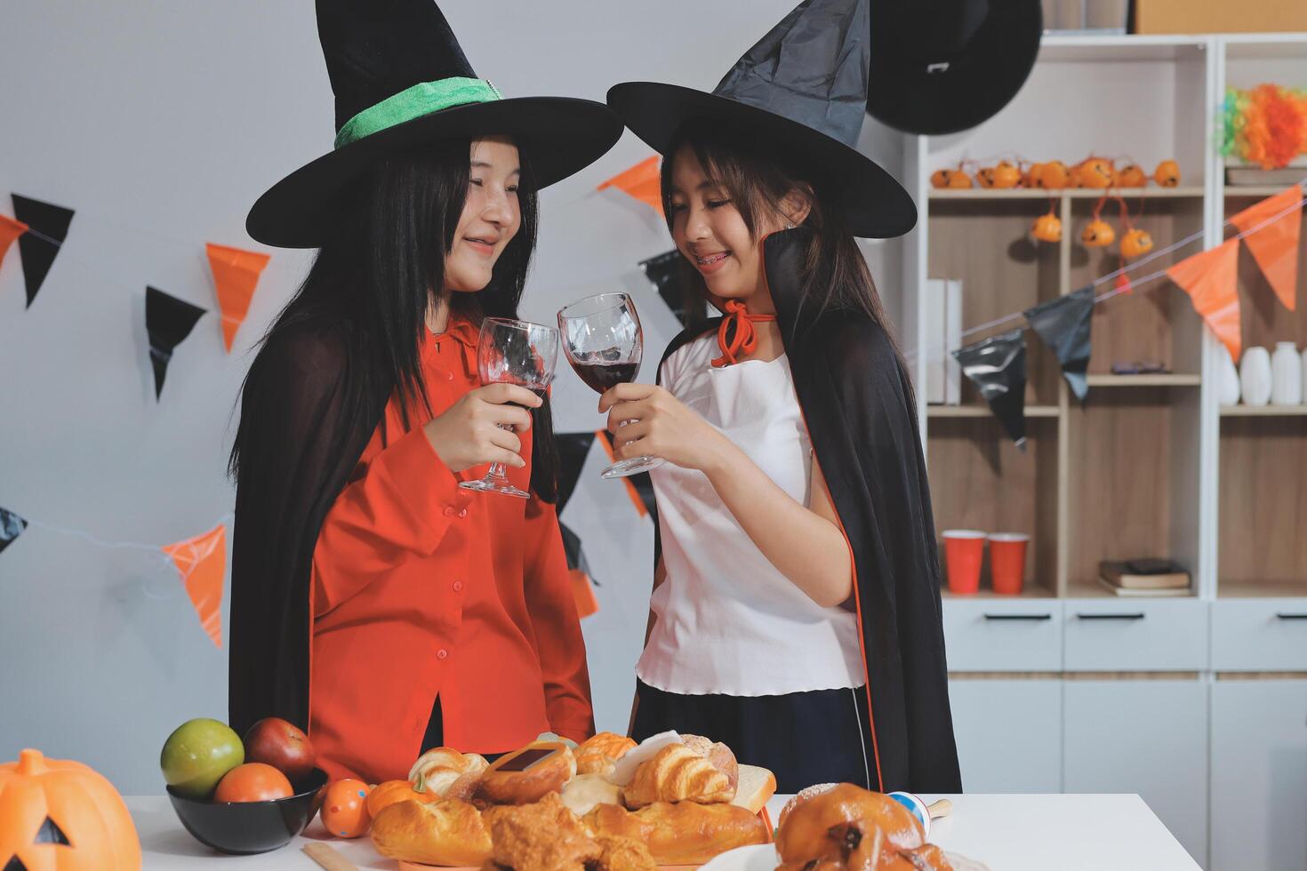 friendship, holiday and people concept - group of happy smiling friends in halloween costumes of vampire, devil, witch and cheetah at home party photo