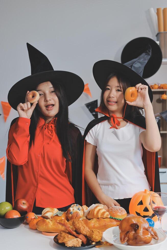 friendship, holiday and people concept - group of happy smiling friends in halloween costumes of vampire, devil, witch and cheetah at home party photo