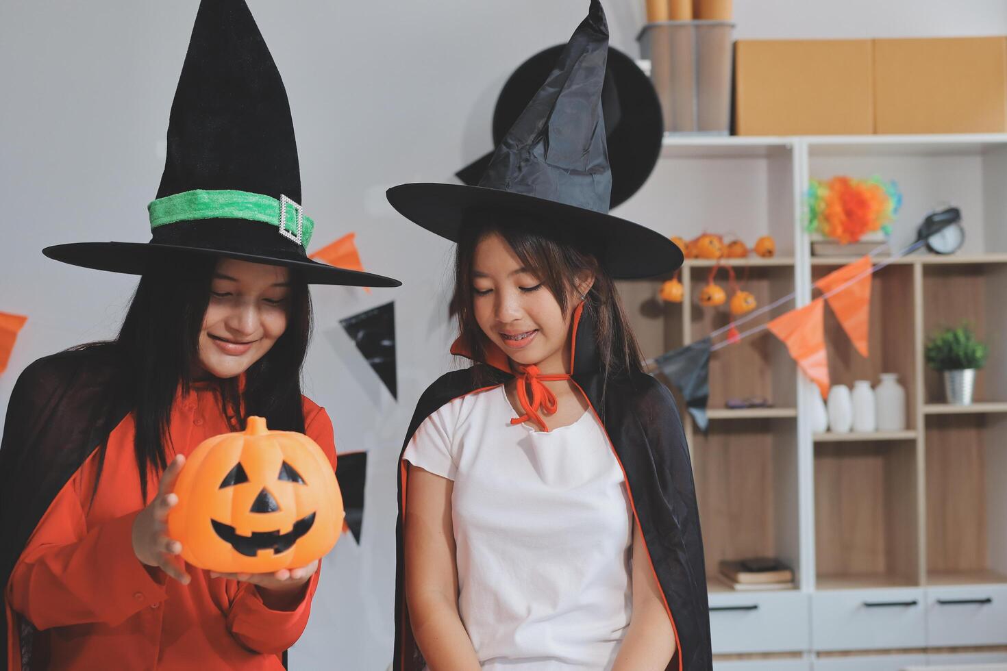 friendship, holiday and people concept - group of happy smiling friends in halloween costumes of vampire, devil, witch and cheetah at home party photo