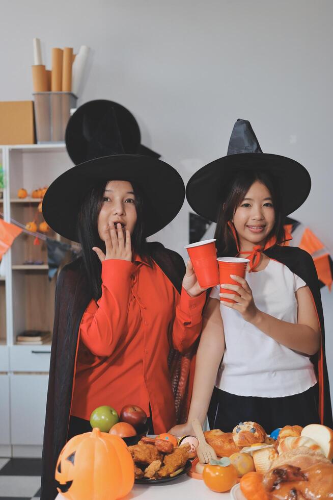 friendship, holiday and people concept - group of happy smiling friends in halloween costumes of vampire, devil, witch and cheetah at home party photo