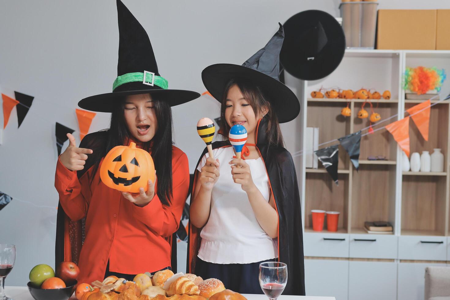friendship, holiday and people concept - group of happy smiling friends in halloween costumes of vampire, devil, witch and cheetah at home party photo