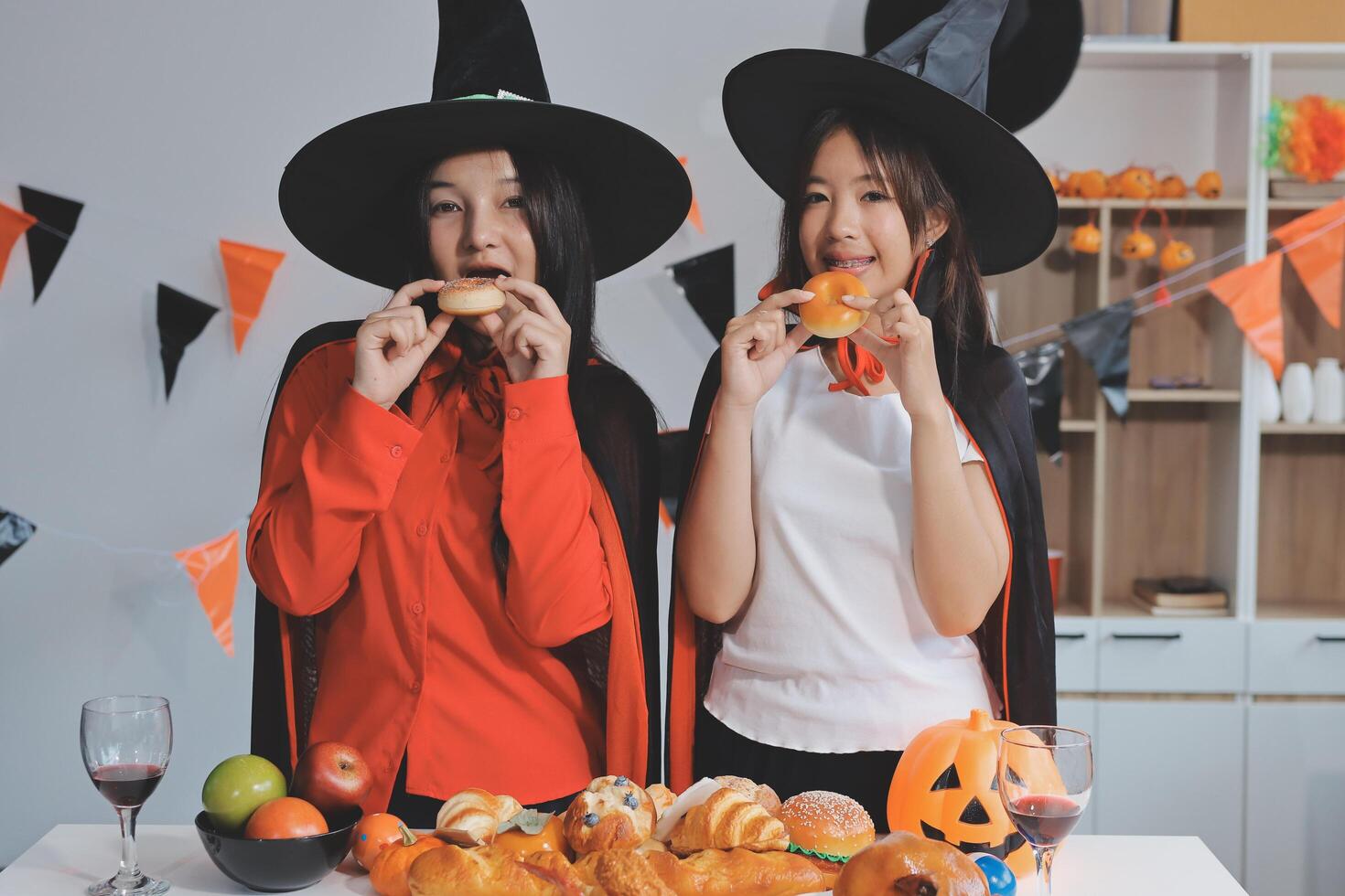 friendship, holiday and people concept - group of happy smiling friends in halloween costumes of vampire, devil, witch and cheetah at home party photo